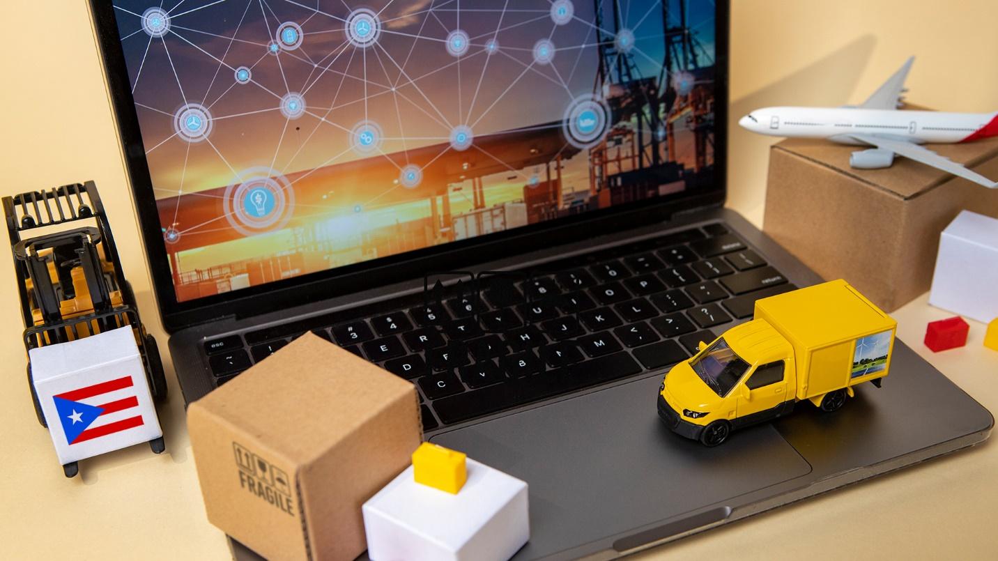 A laptop surrounded by a miniature plane, truck, and moving boxes in a section previewing the tax benefits for export services businesses that move to Puerto Rico.