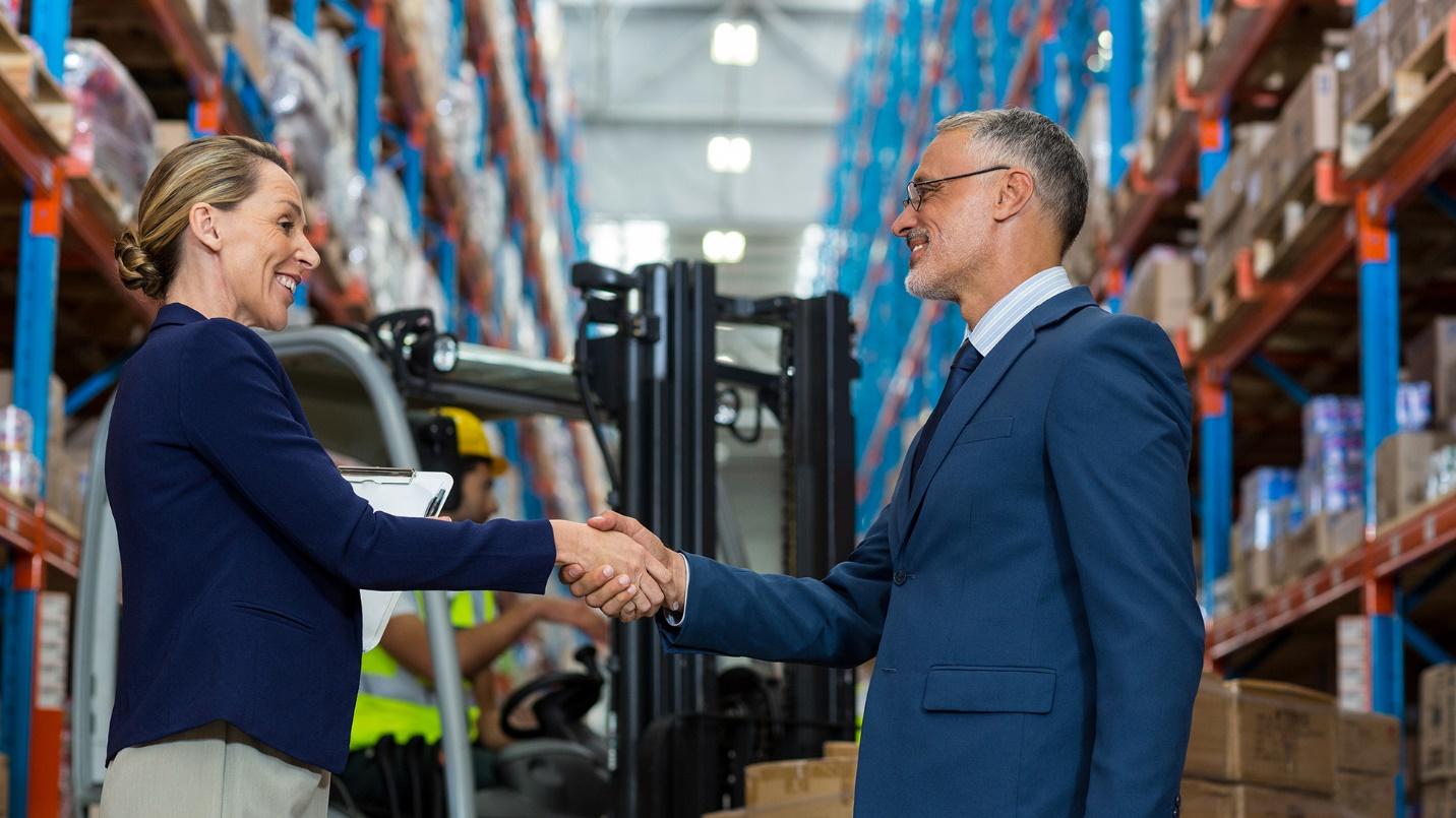 A smiling man and woman shake hands in a store aisle beside someone operating lifting equipment in a section that explains how and why Puerto Rico incentivizes export services.