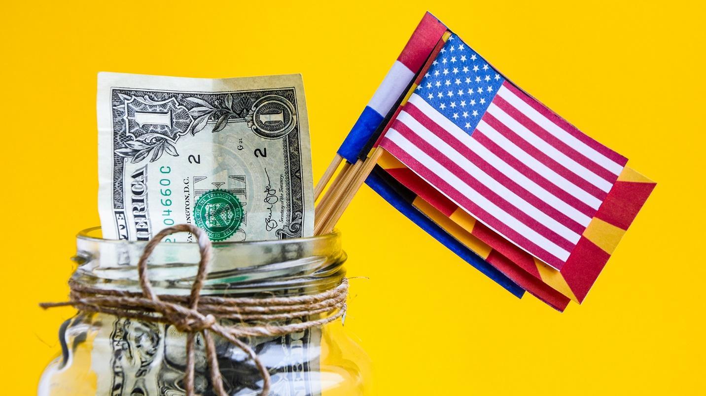 A jar containing a US dollar bill and miniature flags against a yellow background in a section introducing the best tax havens worldwide.