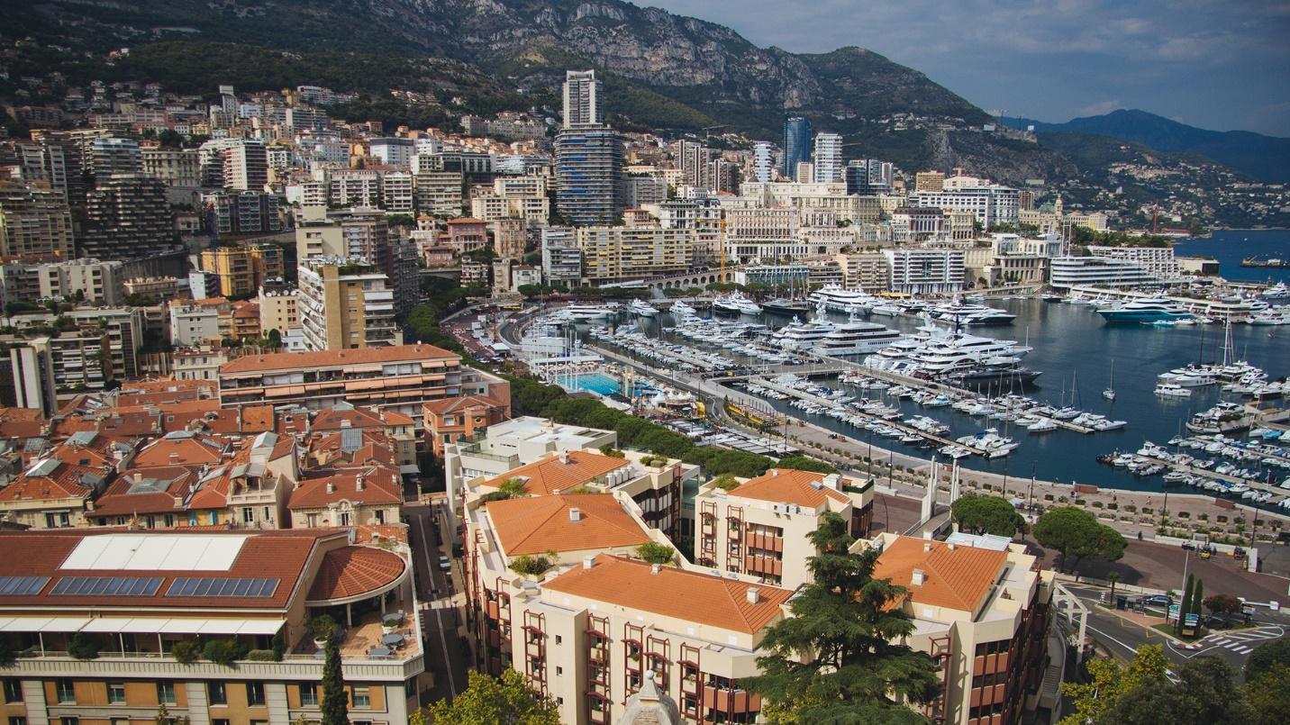 A harbor filled with ships surrounded by buildings and mountains in a section about the tax incentives available in Monaco.
