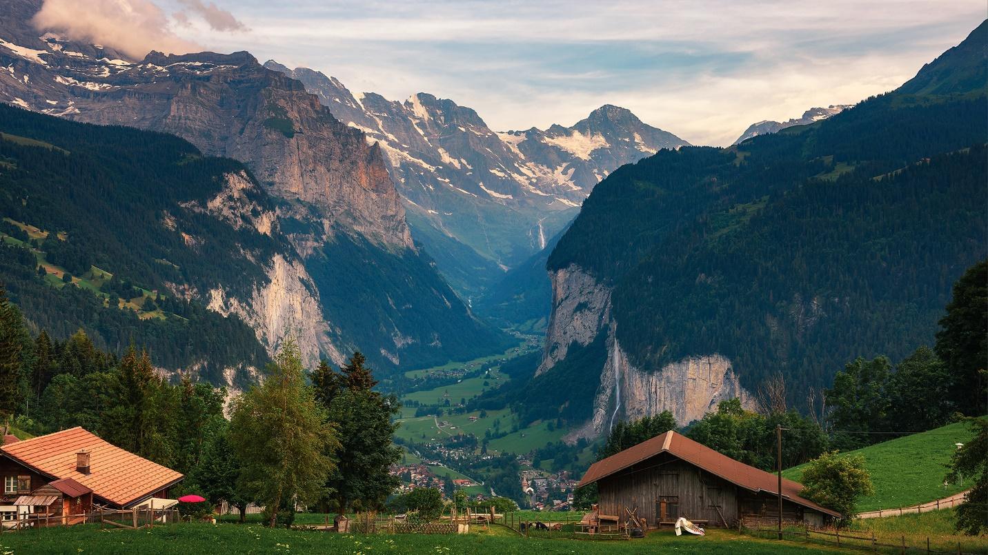 A green valley filled with buildings and surrounded by snow-capped mountains in a section about the tax policies of Switzerland.