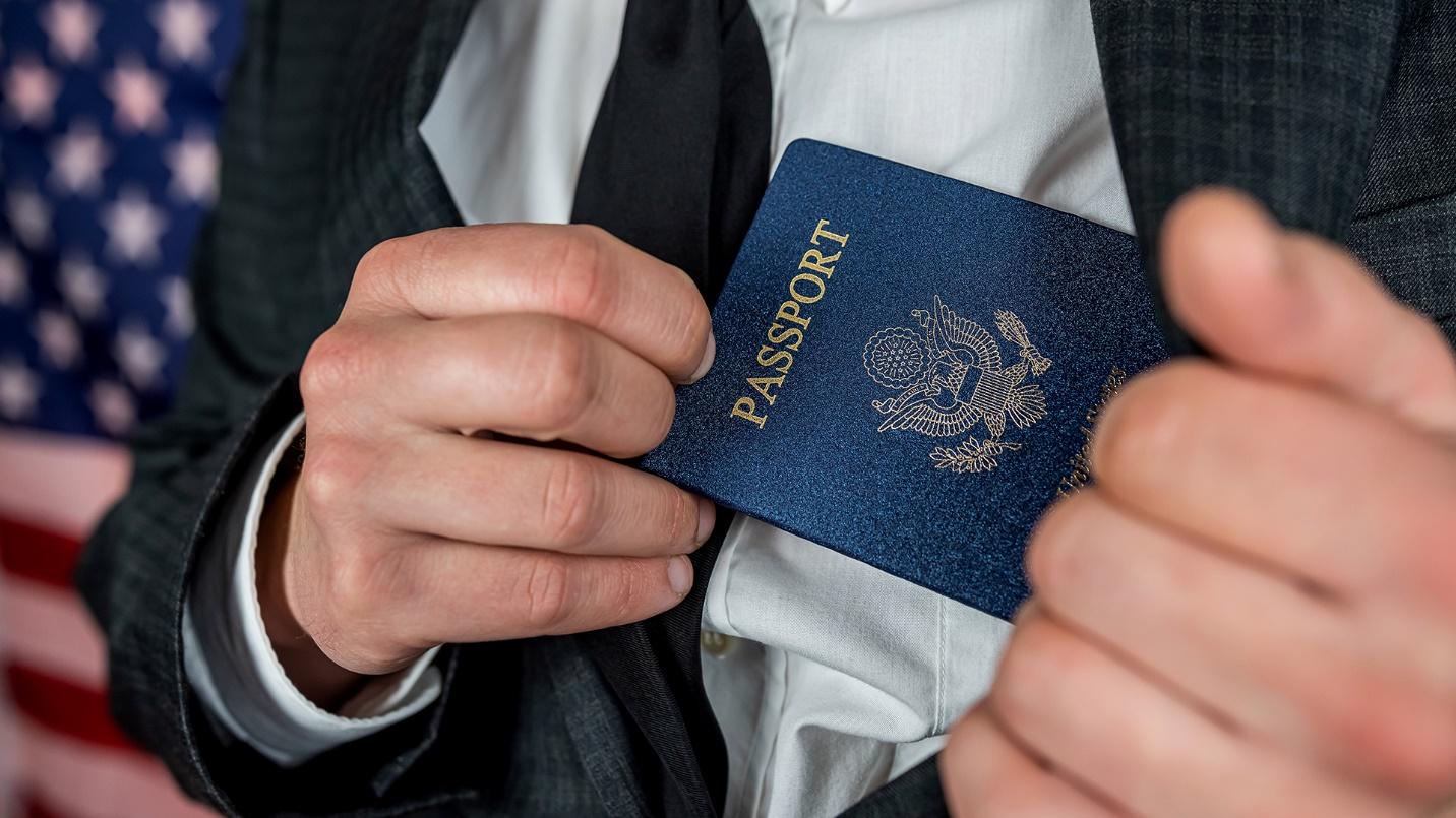 A man in a suit pulls a U.S. passport from his coat pocket in a section describing the history of Puerto Rican citizenship.