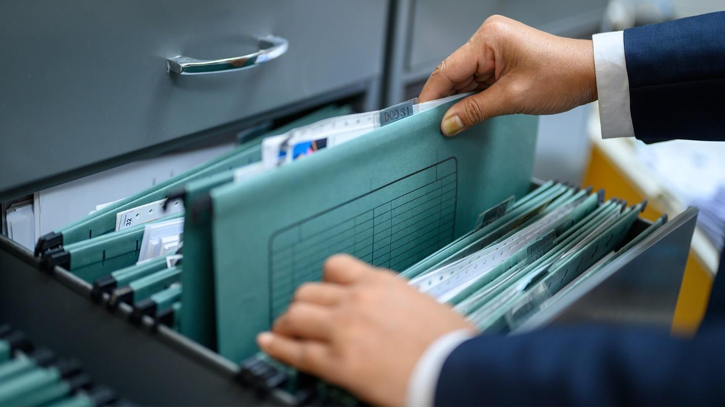 Person removing a file from a filing cabinet.