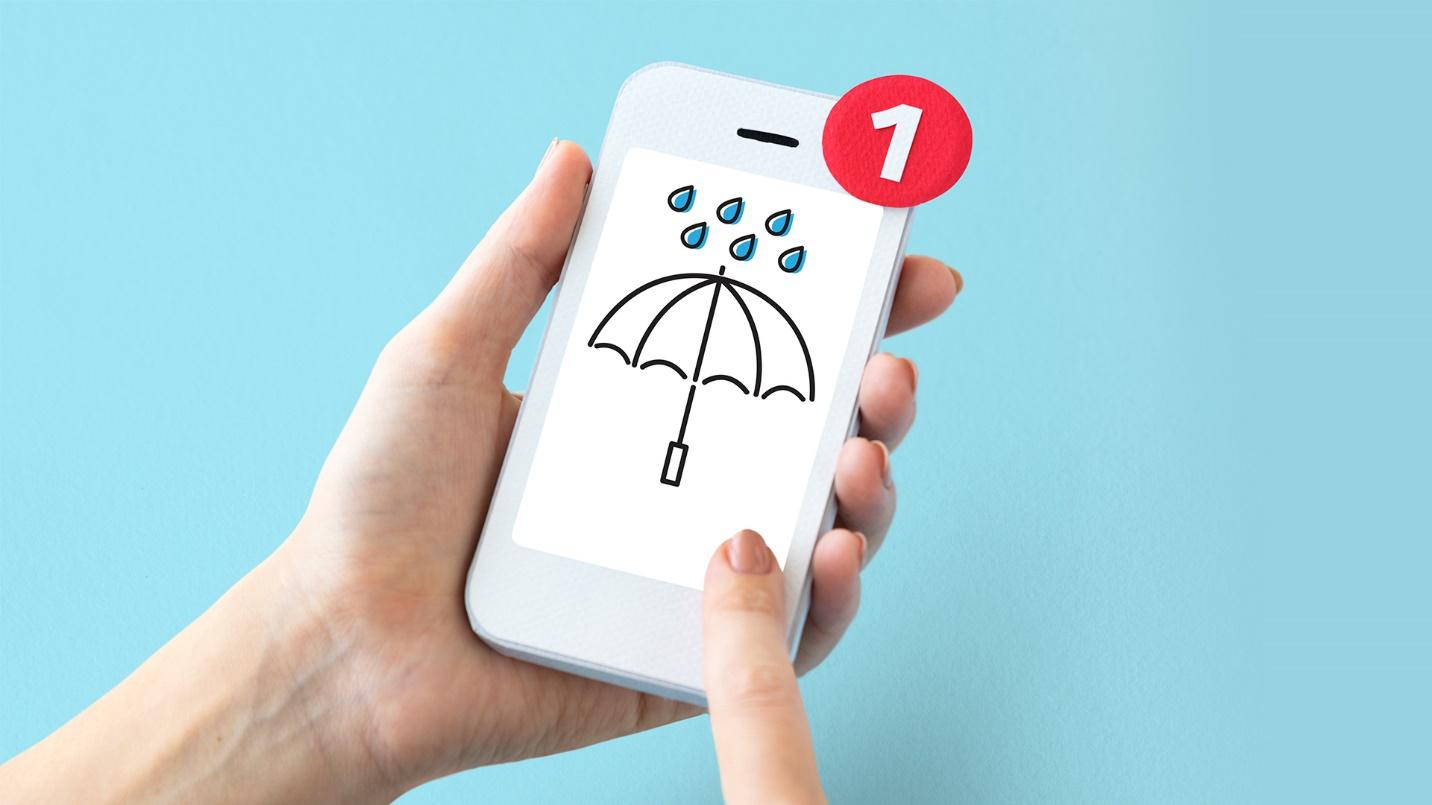 A person holding a smartphone with a screen depicting an umbrella and raindrops in a section about Puerto Rico’s hurricane season.