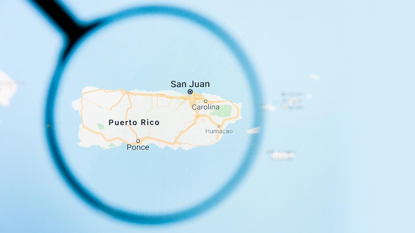 A magnifying glass suspended over a map showing Puerto Rico in a section that defines hurricanes and explains the risk that hurricanes pose to the island.