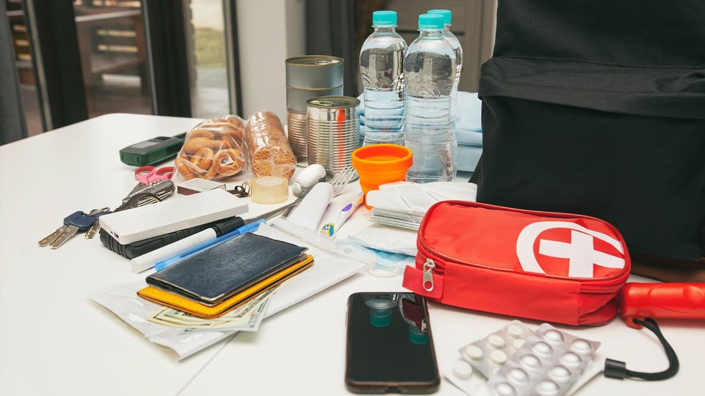 The contents of an emergency supplies kit, including bottled water, canned food, first aid materials, batteries, keys, food, and cash, in a section about how to prepare such a kit in Puerto Rico.