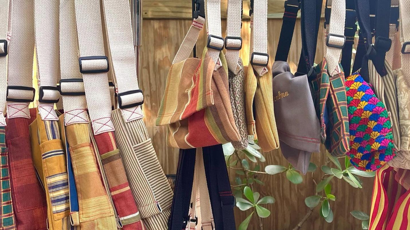 An assortment of colorful handbags in a section about the fashionable and environmentally conscious products at Concalma.