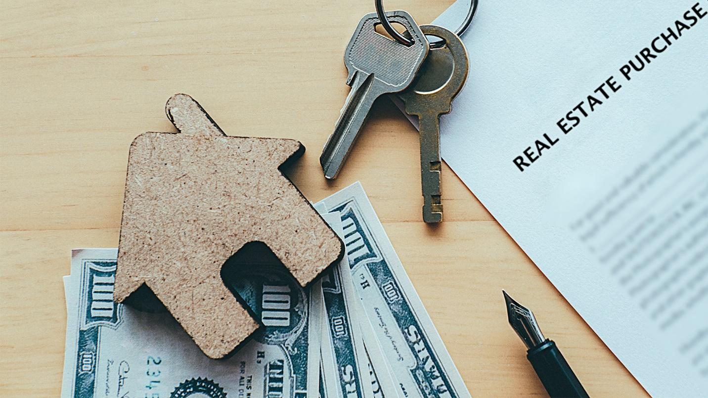 Keys, cash, and papers rest on a table in a section about how each Act 60 decree holder must purchase real estate to use as their primary residence in Puerto Rico within two years of obtaining the decree.
