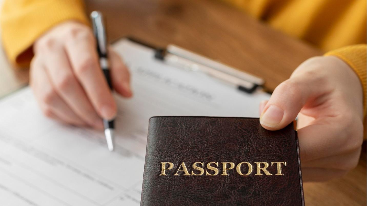 A person holds a passport and a pen above a clipboard and forms in a section about why acquiring a separate Puerto Rico passport is unnecessary.

