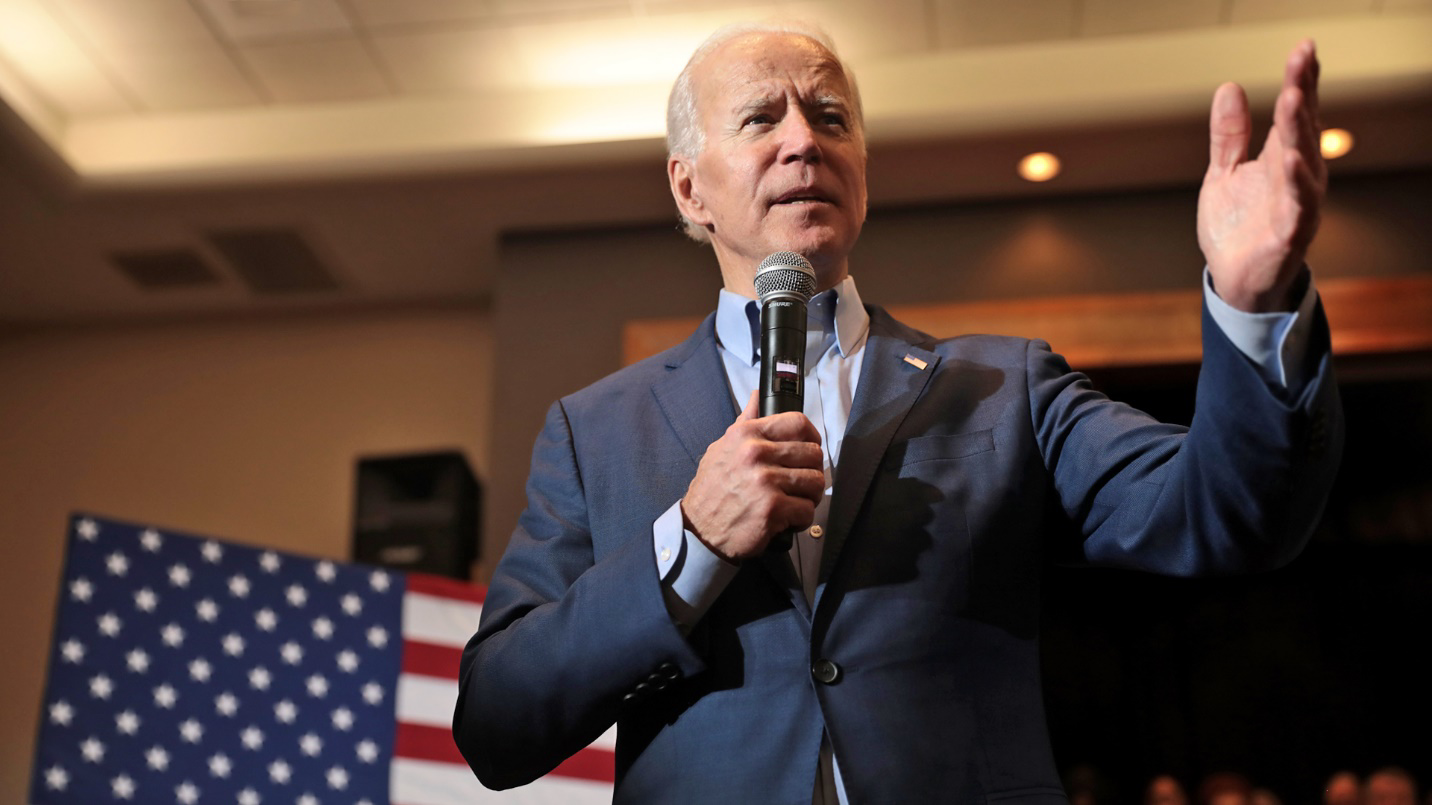 President Biden gives a speech in front of an American flag in a section about Puerto Rico’s tax incentives and increased federal investment in the island.