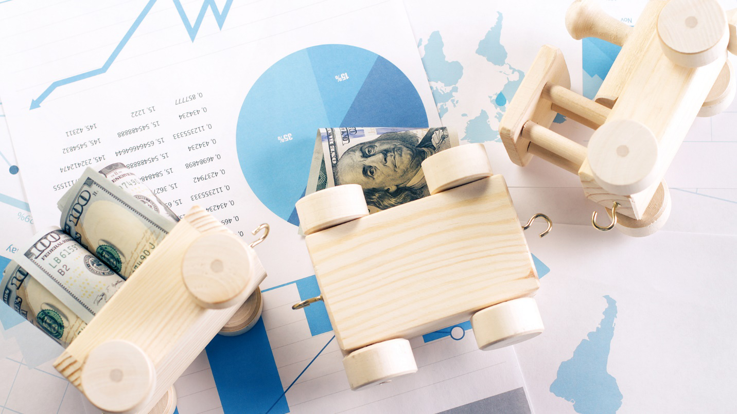 Wooden toys and currency on top of documents filled with graphs and maps in a section about relocating to Puerto Rico under the Act 60 program.
