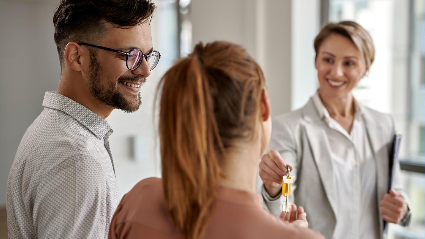 A man and woman take the keys from a smiling real estate agent in an introduction to the advantages of owning luxury real estate in Puerto Rico.