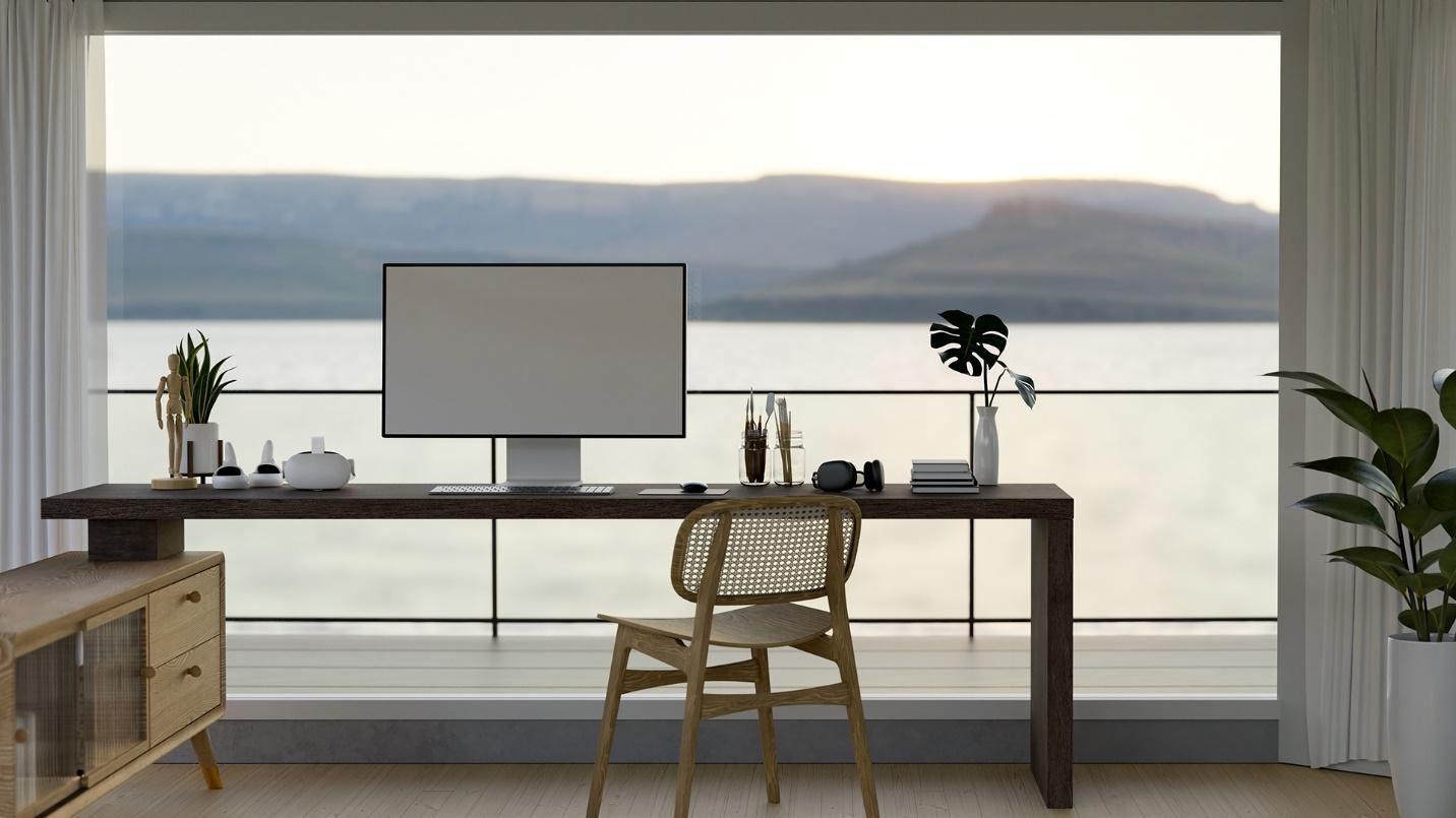 A desk, chair, and computer in front of a giant window with a view of the sea and mountains in a section previewing the benefits of owning luxury real estate in Puerto Rico.
