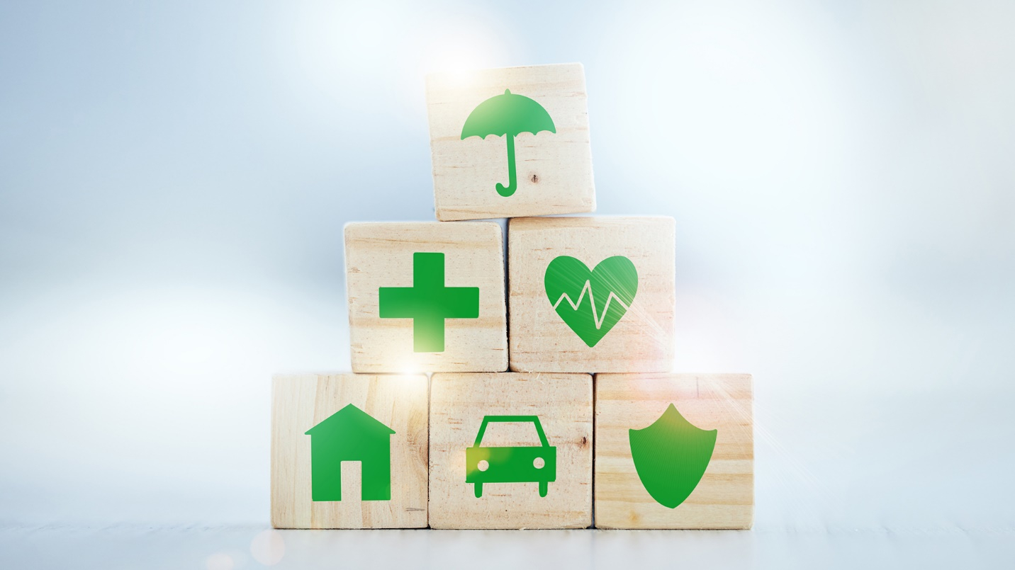 A stack of six wooden blocks, each showing its own green icon: umbrella, cross, heart, house, car, and shield.