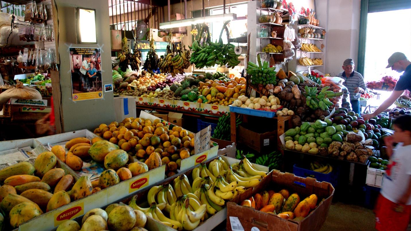 Market stalls overflowing with colorful produce in a section about what La Placita de Santurce offers.