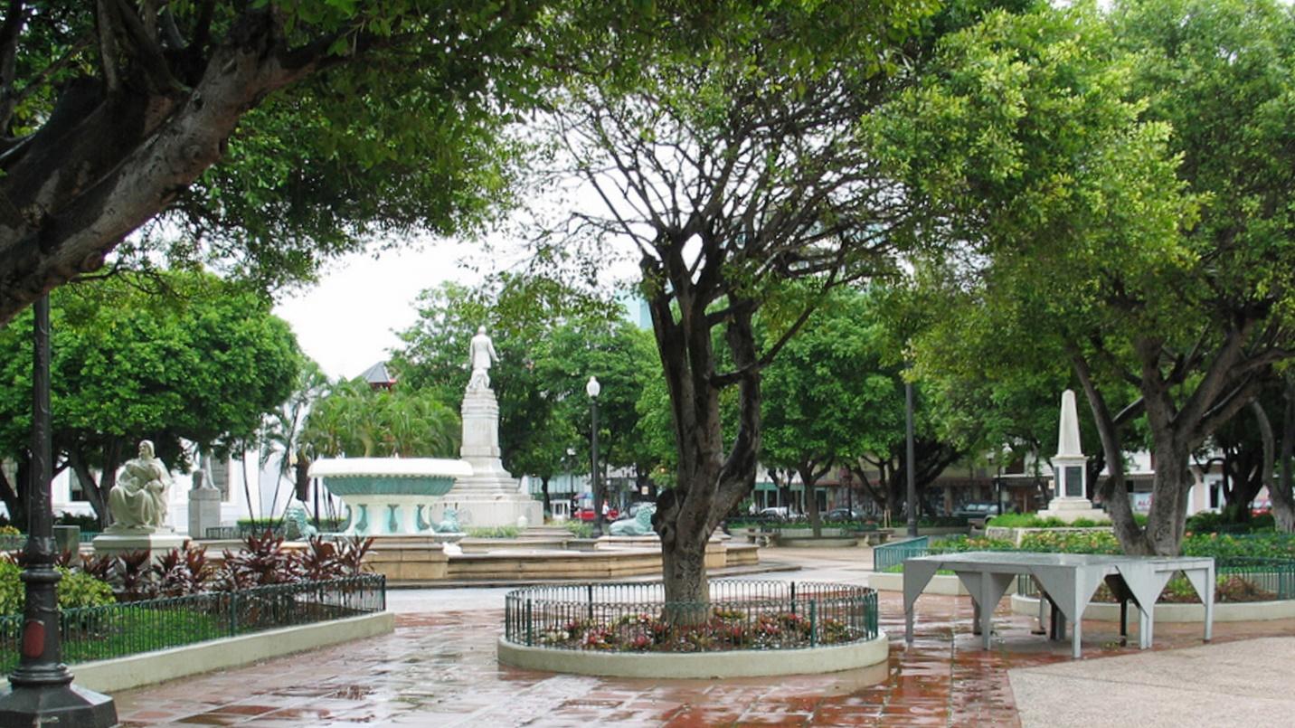 Stone statues and monuments adorn a tree-filled park in a section about Plaza las Delicias in Ponce, Puerto Rico.