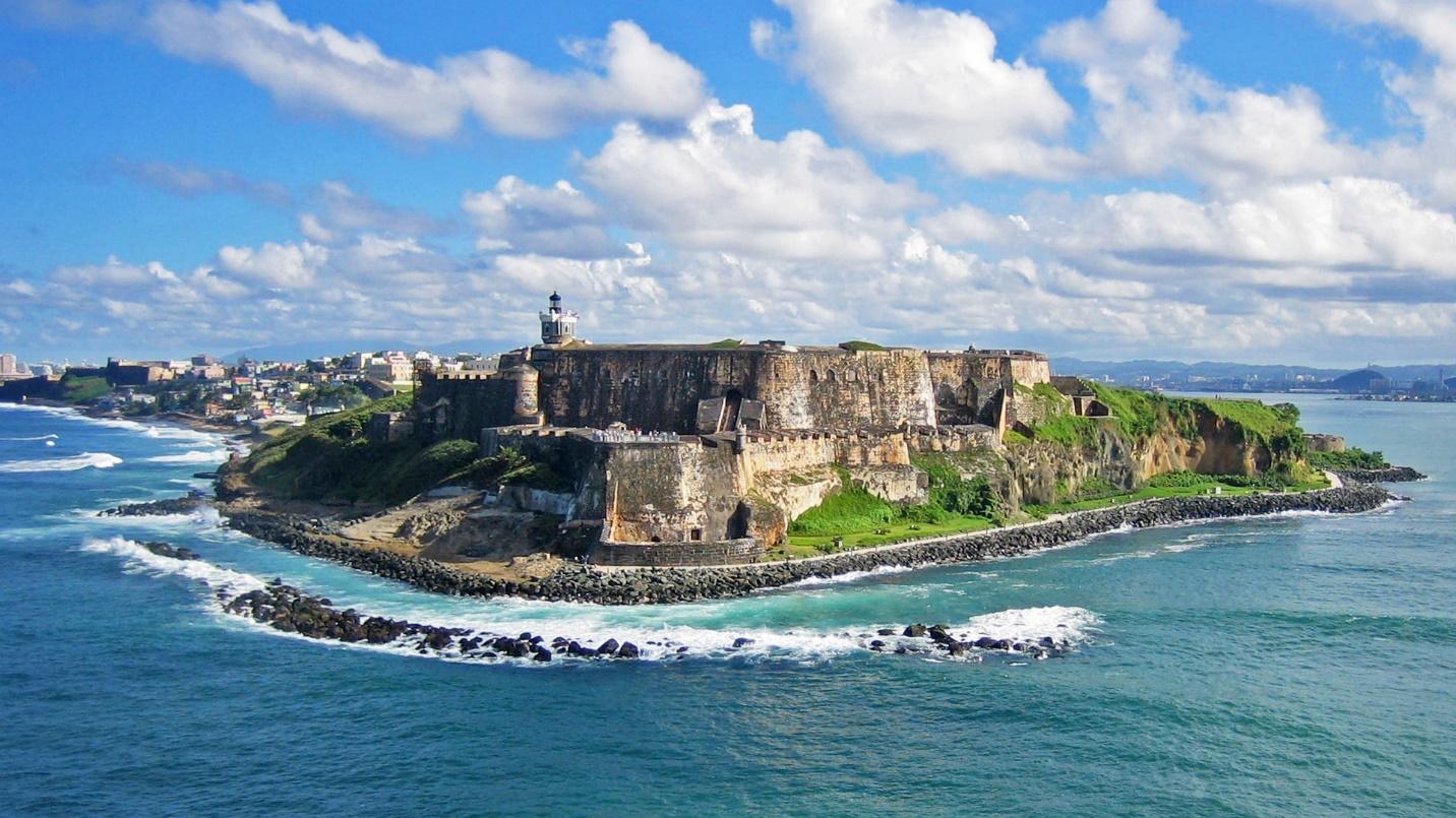 The coastal fort El Morro is framed by blue water and skies in a section about the history of the island and San Juan.