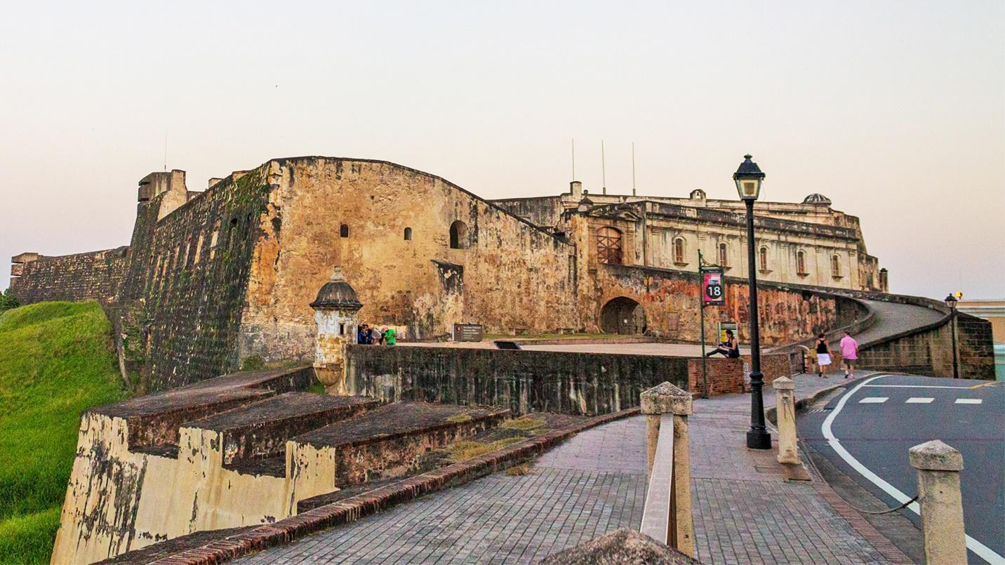 A paved walkway leads to the entrance of Fort San Cristobal, in a section describing its history and highlights for visitors.