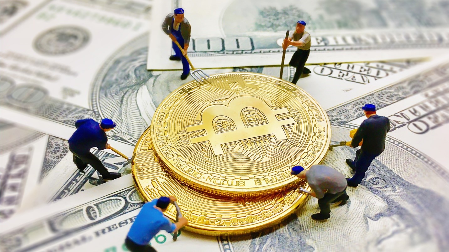 Six figurines of workers surround two golden Bitcoins on a floor made of one-hundred-dollar bills in a section explaining how moving to a crypto-friendly destination can help preserve a crypto investor’s earnings.