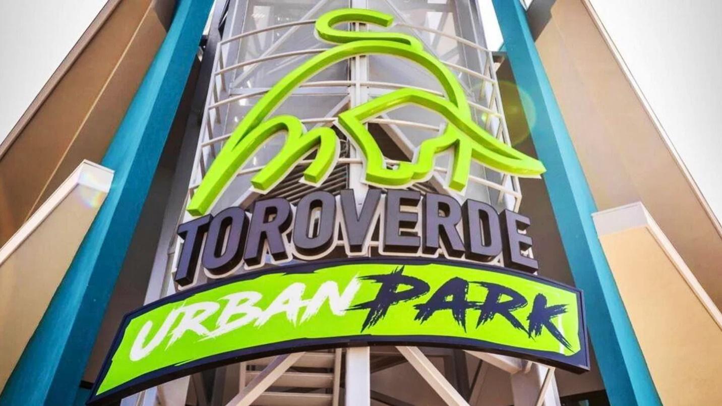 A building displays a sign that reads “Toro Verde Urban Park” in a section describing the adventure park and its tour offerings.