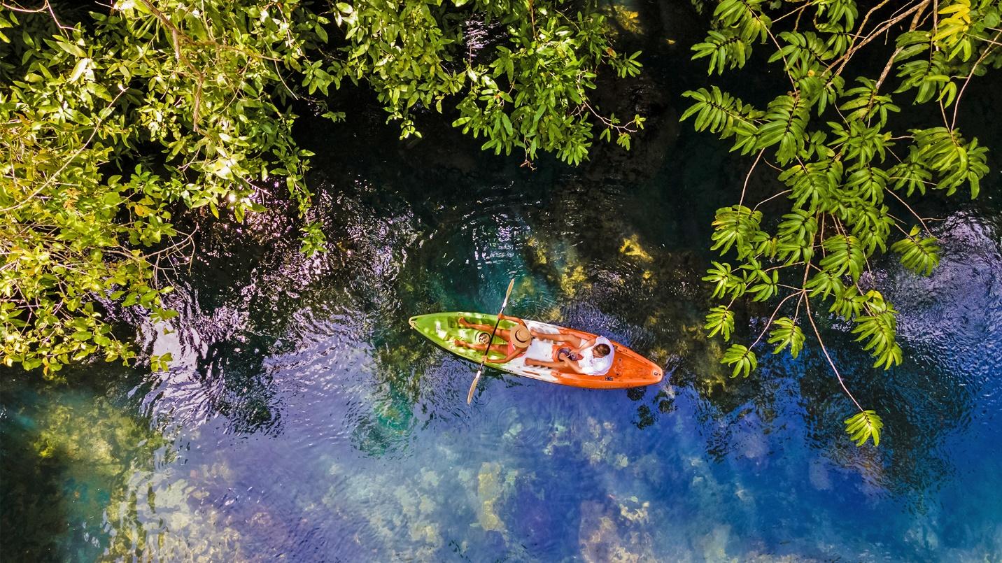 Two kayakers make their way through water surrounded by trees in a section about tour options in Fajardo’s bioluminescent lagoon.