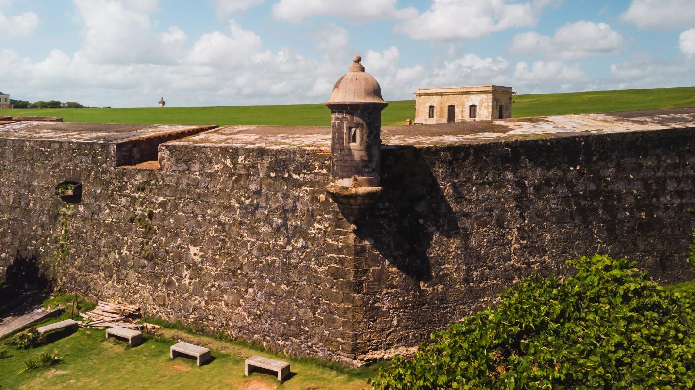 A section of the walls at Castillo San Felipe del Morro surrounded by grass and trees.