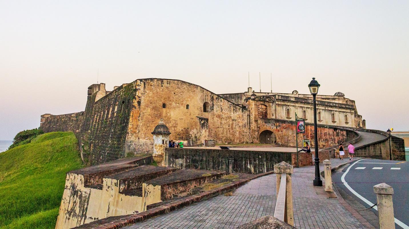 A paved walkway leads to a curved ramp at the walls of Castillo San Cristobal in Old San Juan.