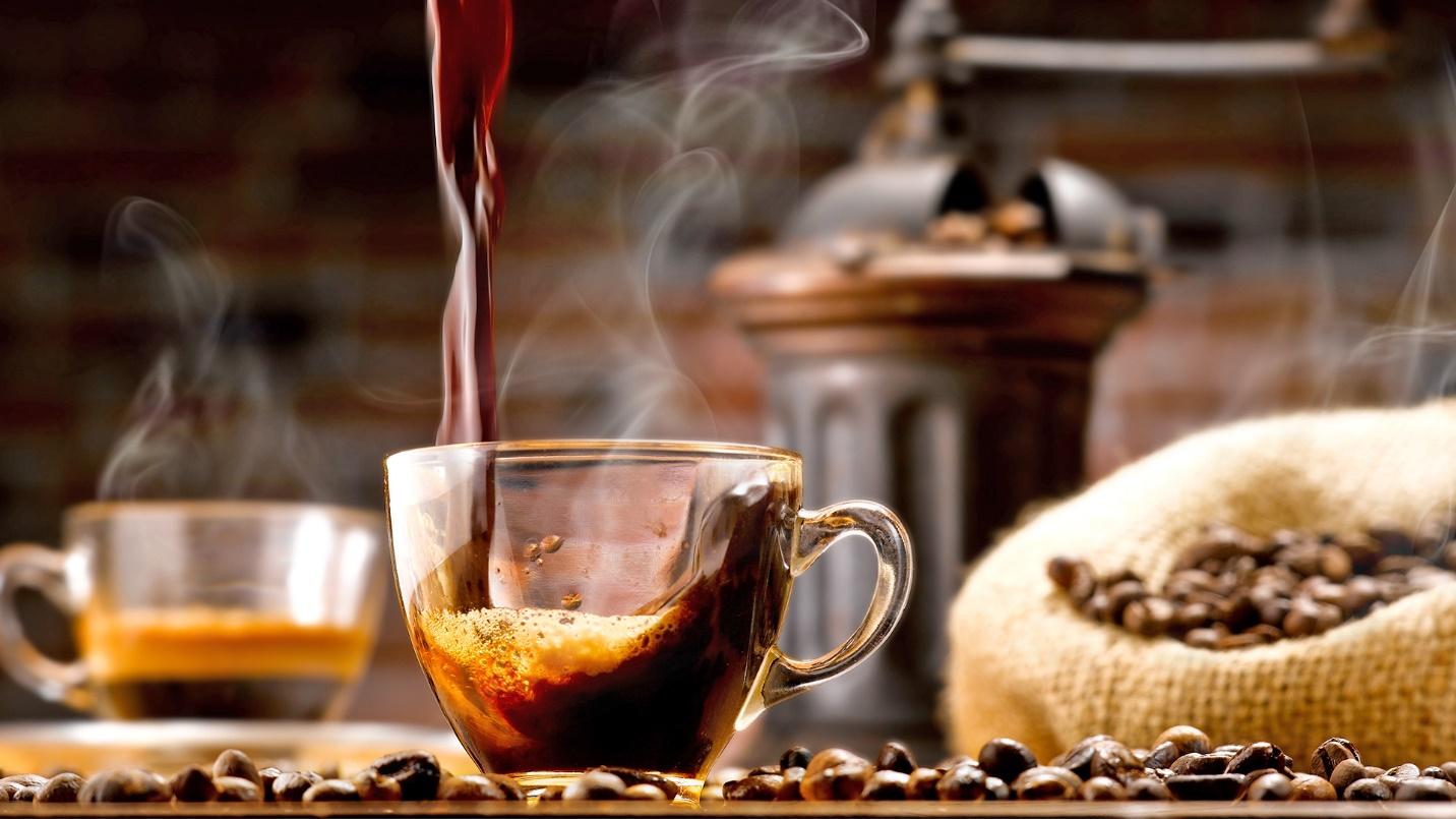 Fresh hot coffee being poured into a glass cup surrounded by coffee beans in a section describing Puerto Rican coffee.