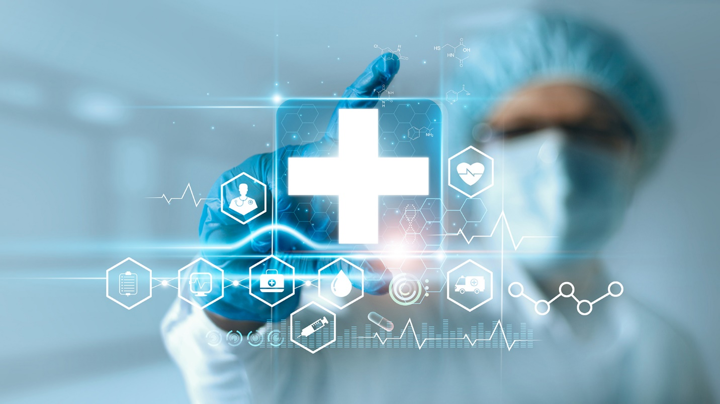 A healthcare worker wearing a mask, gloves, and bouffant cap gestures at a digital display of medical symbols including a cross, heart, and syringe.