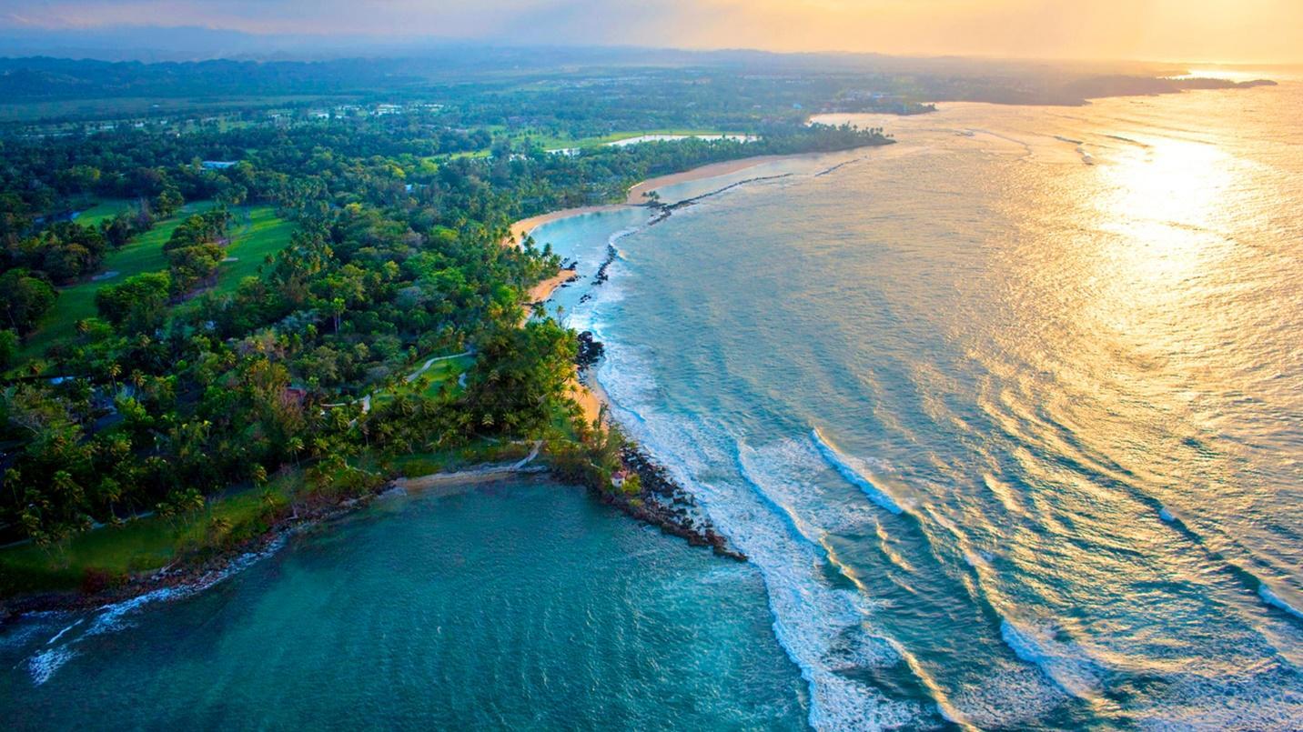The setting sun illuminates the sea, beach, and trees in a section introducing the benefits of residing in this exclusive neighborhood.
