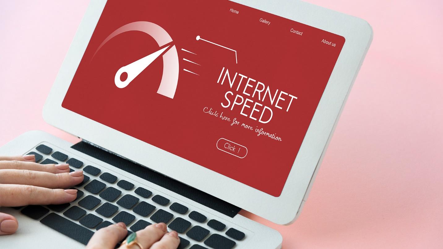 A person types the keyboard of a laptop computer that displays an internet speed test in a section about internet connectivity in the neighborhood.