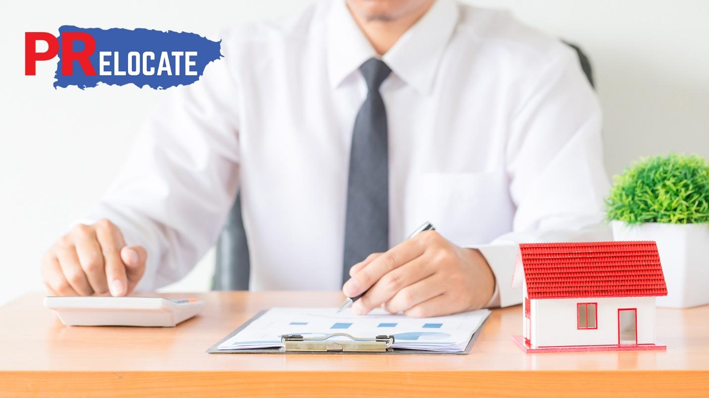 A man dressed in a white shirt and gray tie sits at a desk with a clipboard, calculator, and model house in a section describing PRelocate’s real estate brokerage services.