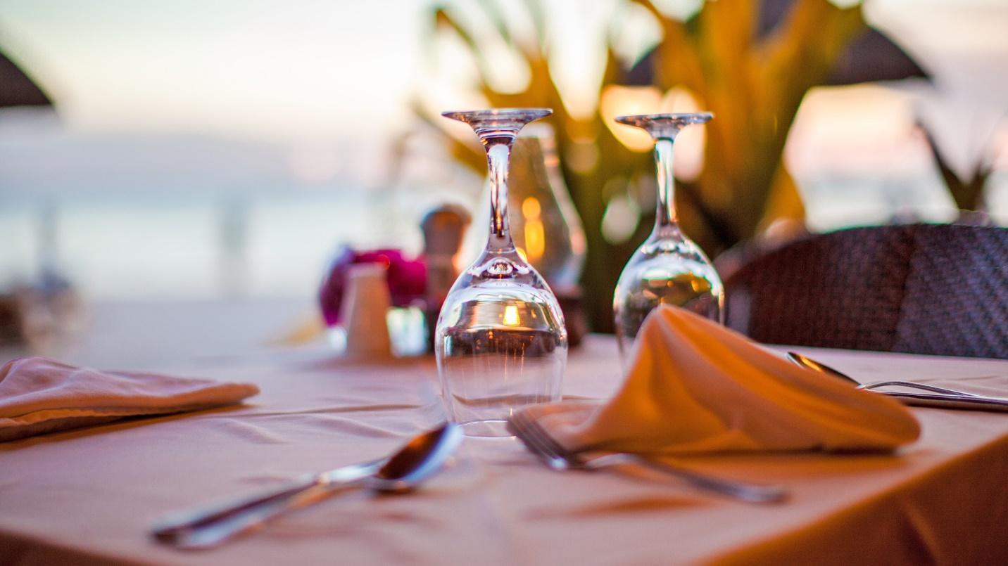 A table set with glasses and utensils by the sea in a section about restaurants and shopping.