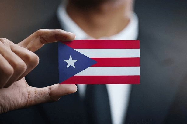 A man in a suit holds a business card that displays the Puerto Rican flag in a section previewing the issues connected to Puerto Rican citizenship.