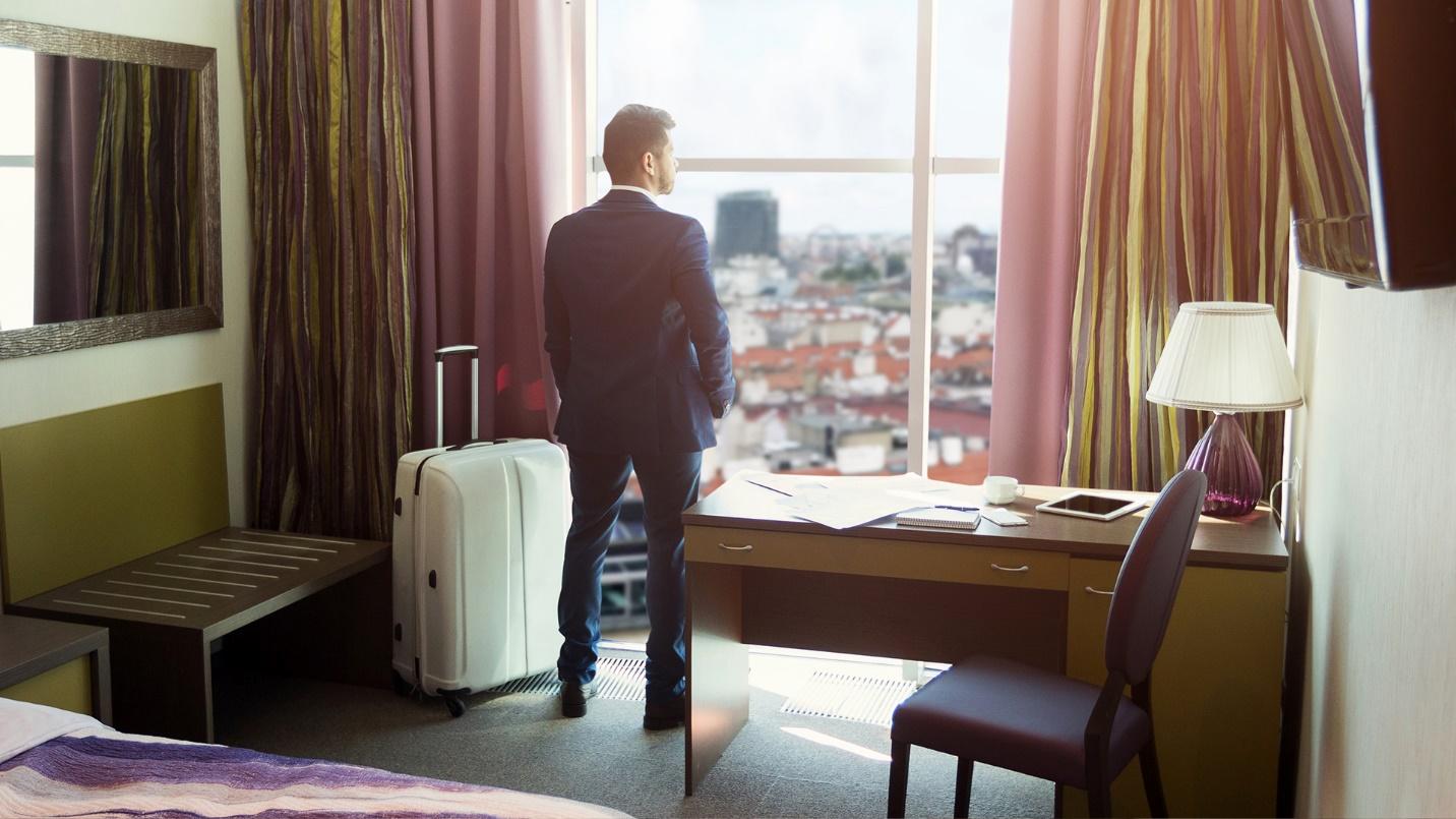 A man in a suit stares from his hotel room window out at the city in a section describing business-friendly accommodations in Puerto Rico. 