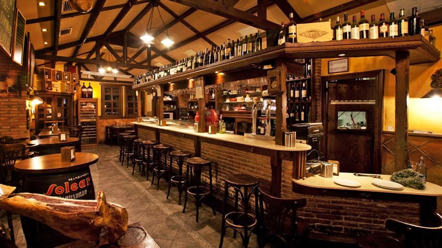 A bar, chairs, and tables in a section describing Entrevinos wine bar and steak house in Isla Verde. 