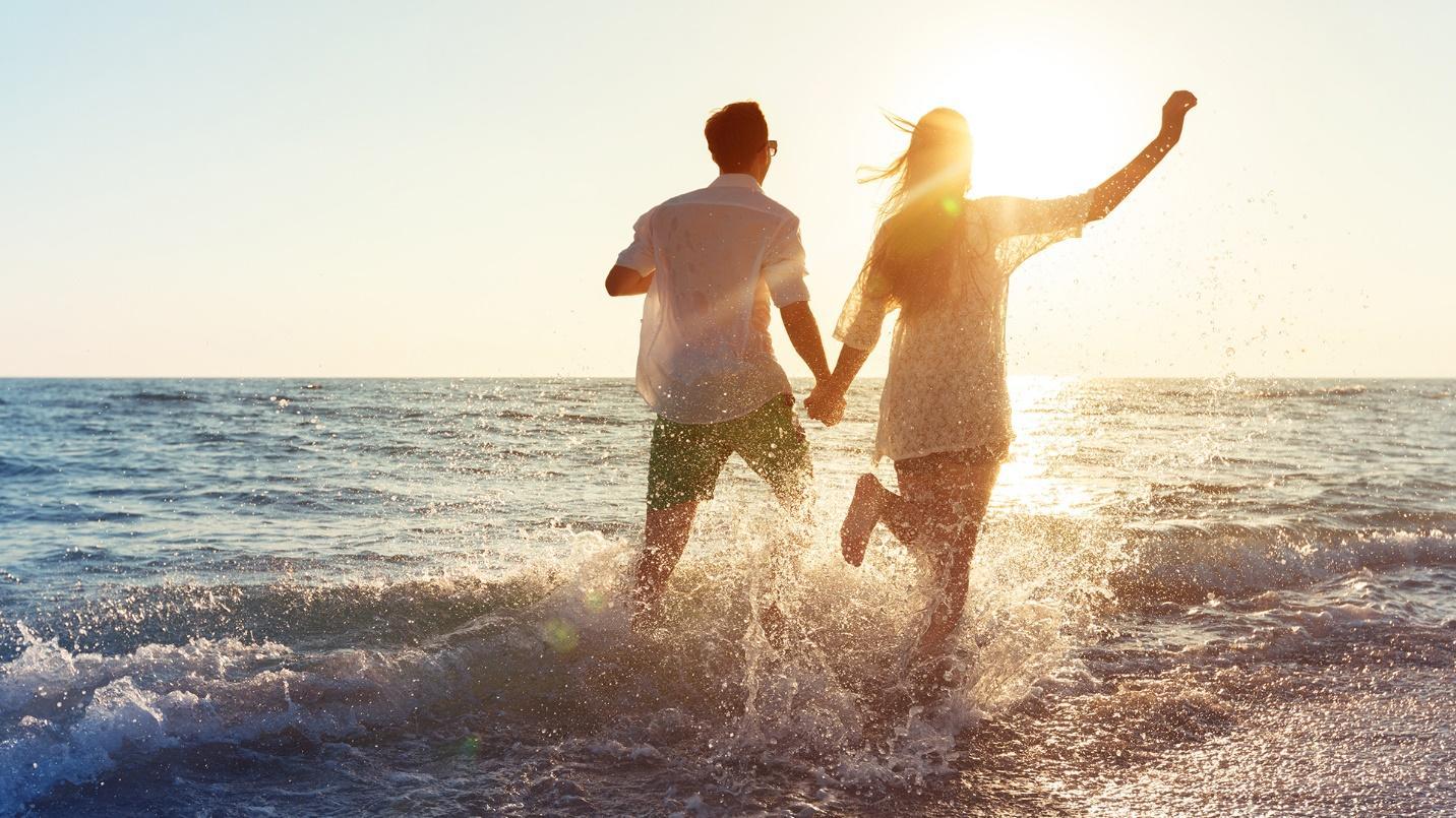 A man and woman hold hands while they run through the surf at the beach in a section about Puerto Rico’s 300 beaches. 