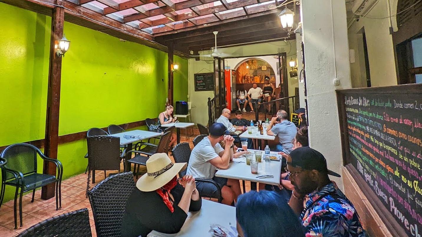 Diners sit at tables and on a bench in a section about the cuisine at Tropical Taste, a restaurant in Old San Juan. 