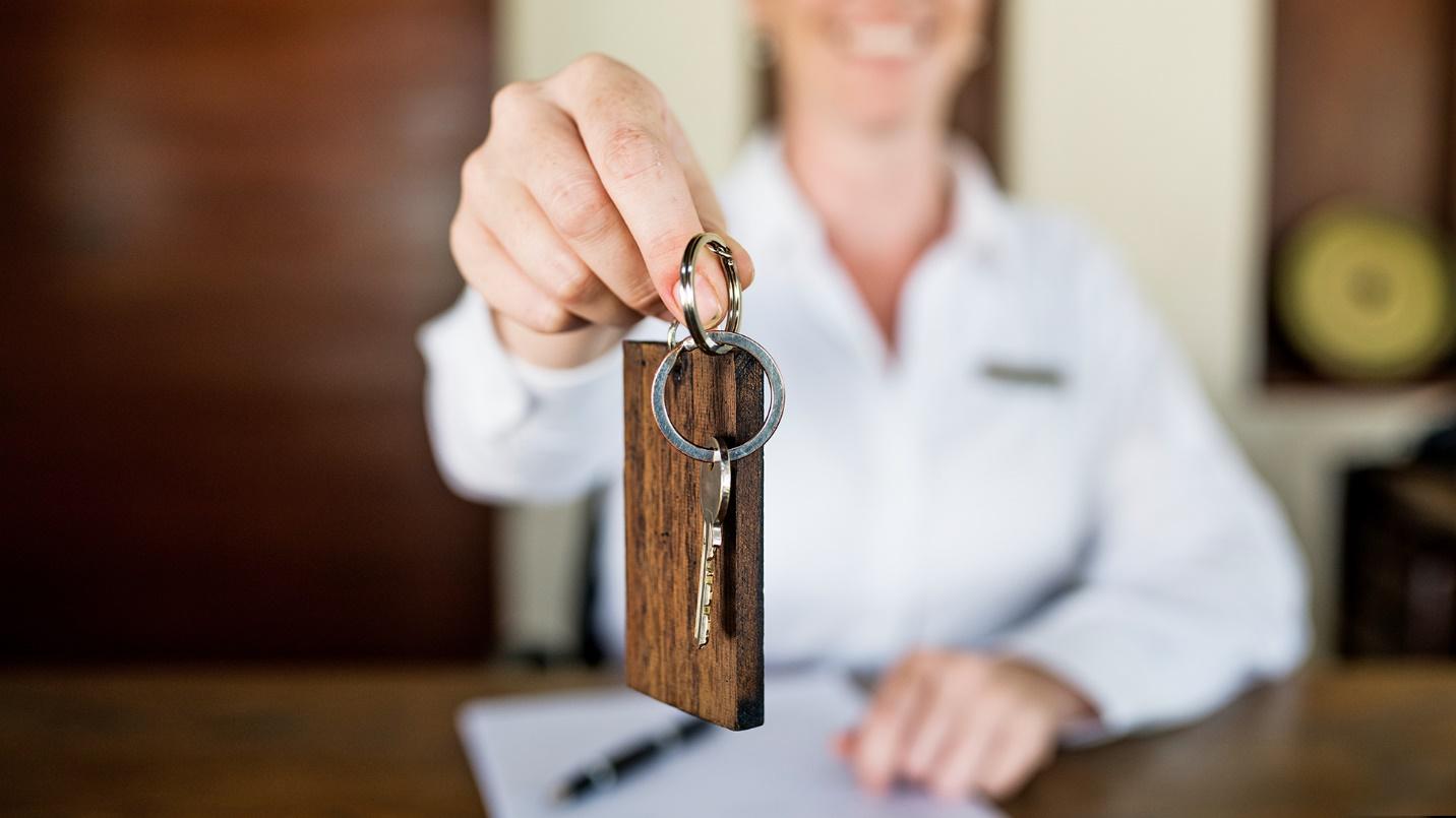 A smiling woman at a desk holds out a keychain in a section describing hotels in San Juan. 