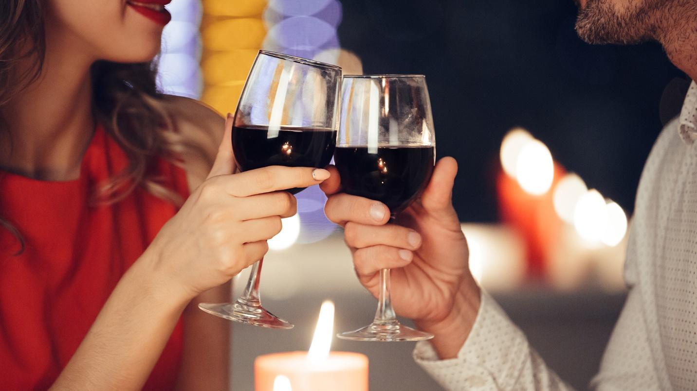 A couple clink their wine glasses together while surrounded by candles in a section about Marmalade Restaurant & Bar, renowned for its romantic ambience. 