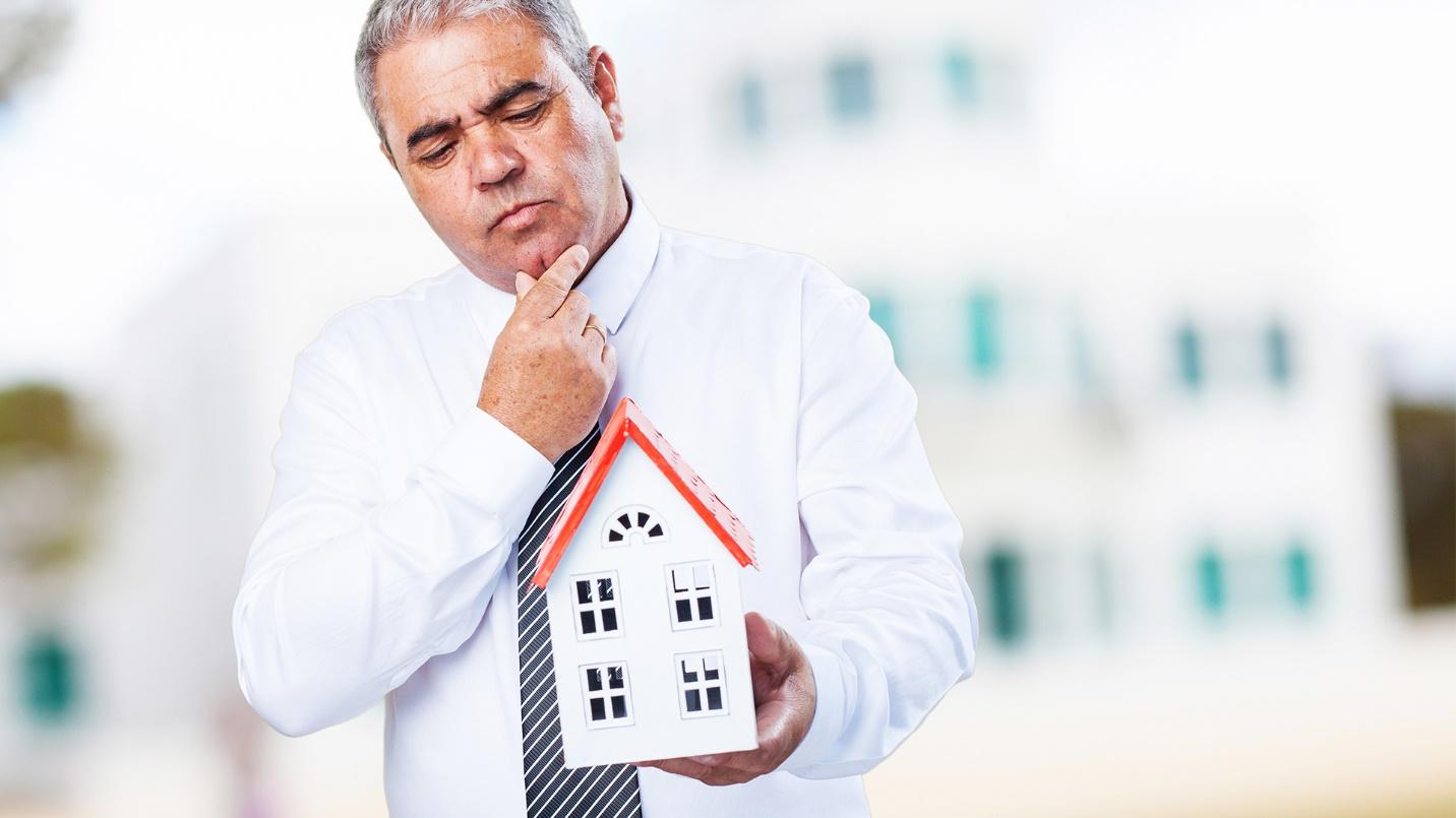 A gray-haired man dressed in a white shirt and black tie strokes his chin and stares thoughtfully at a model house in a section about how prospective residents should work with landlords.
