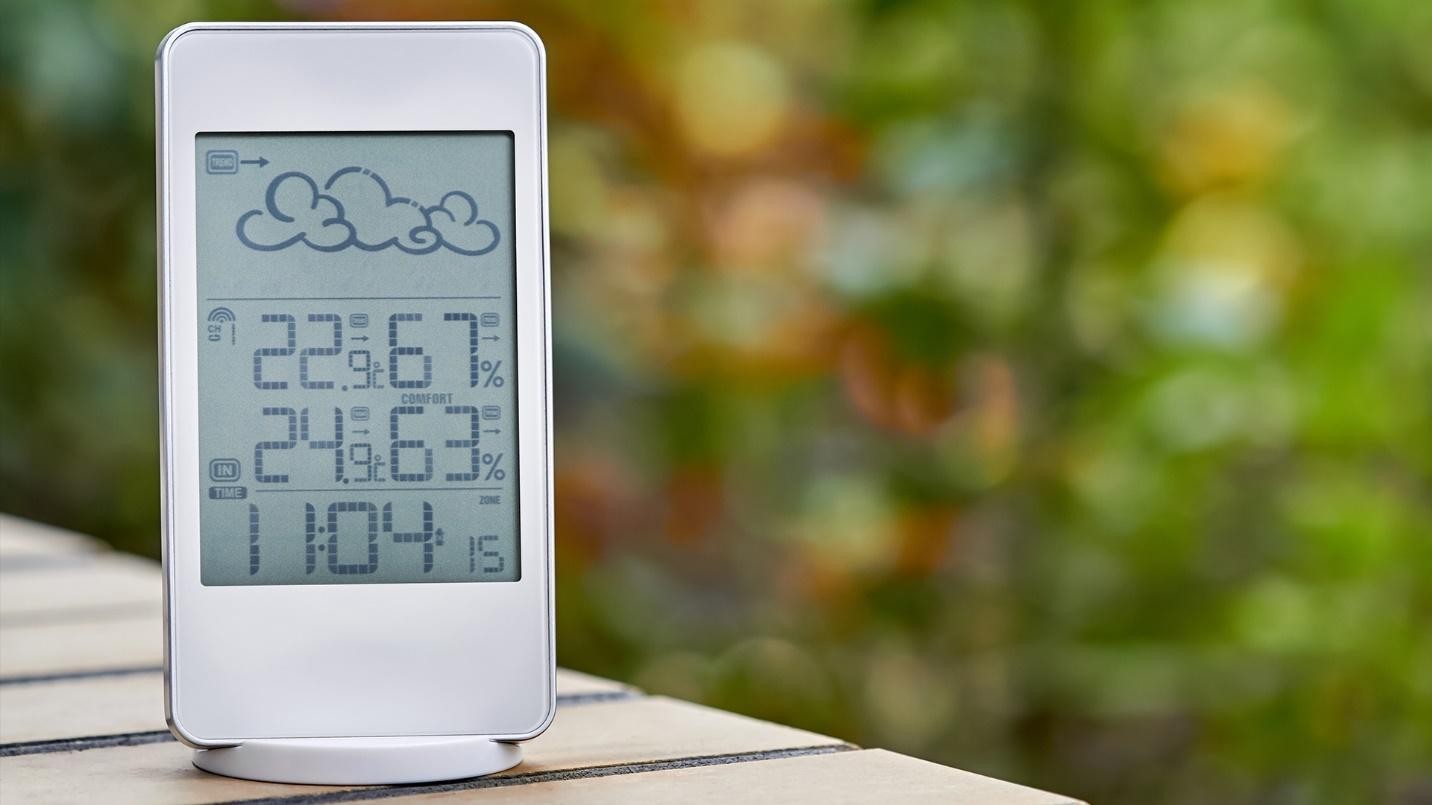 An outdoor digital weather station rests on a table in a section describing the weather and risk of hurricanes in Condado. 
