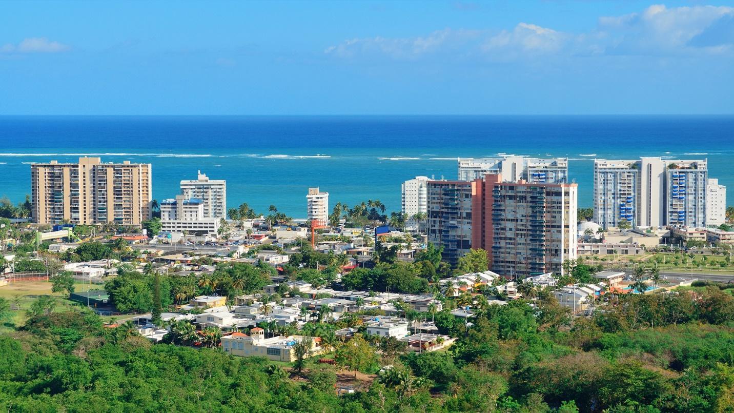 High-rise buildings and trees by the sea in a section that describes the advantages of relocating to Condado.
