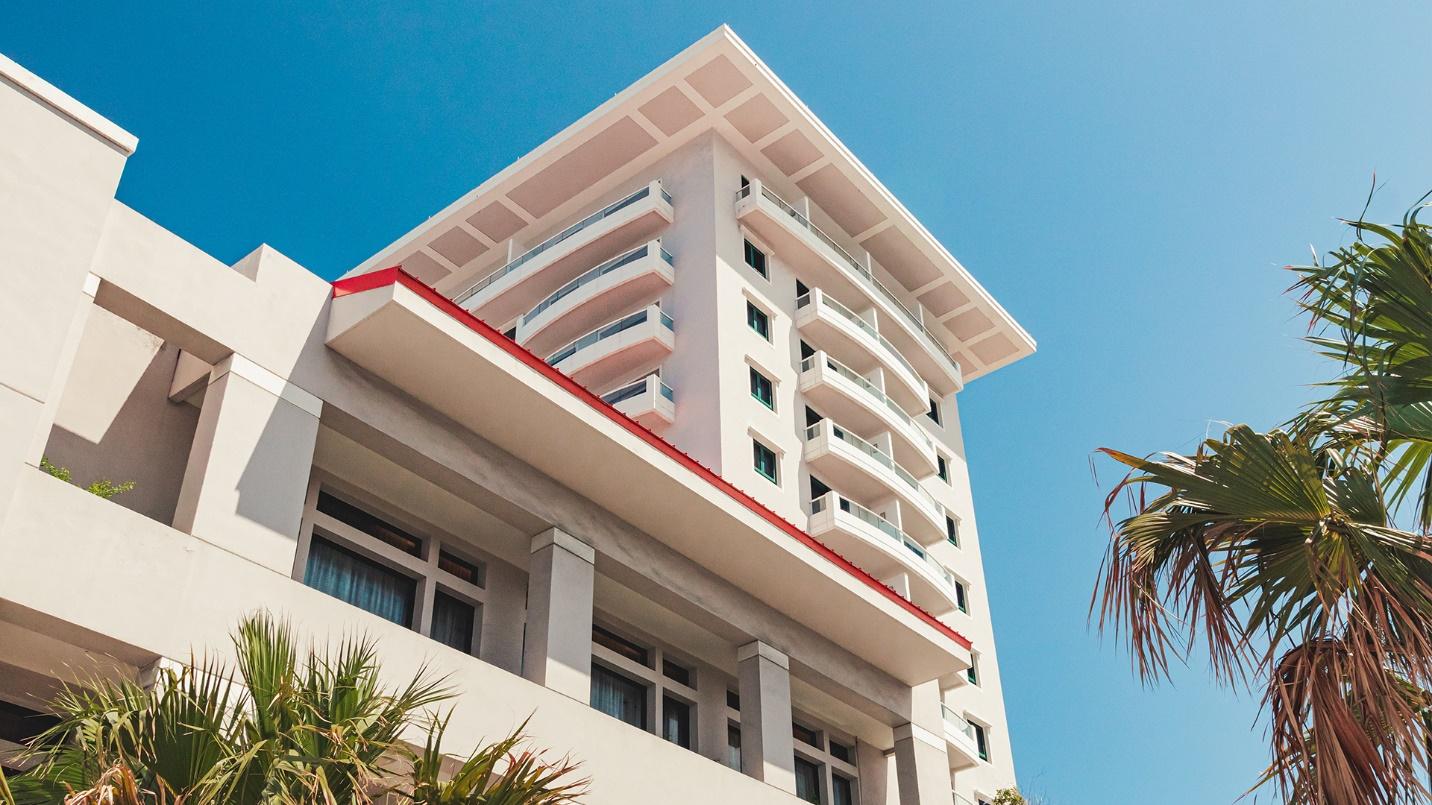 A high-rise building and trees against a blue sky in a section describing the cost of renting in Condado. 
