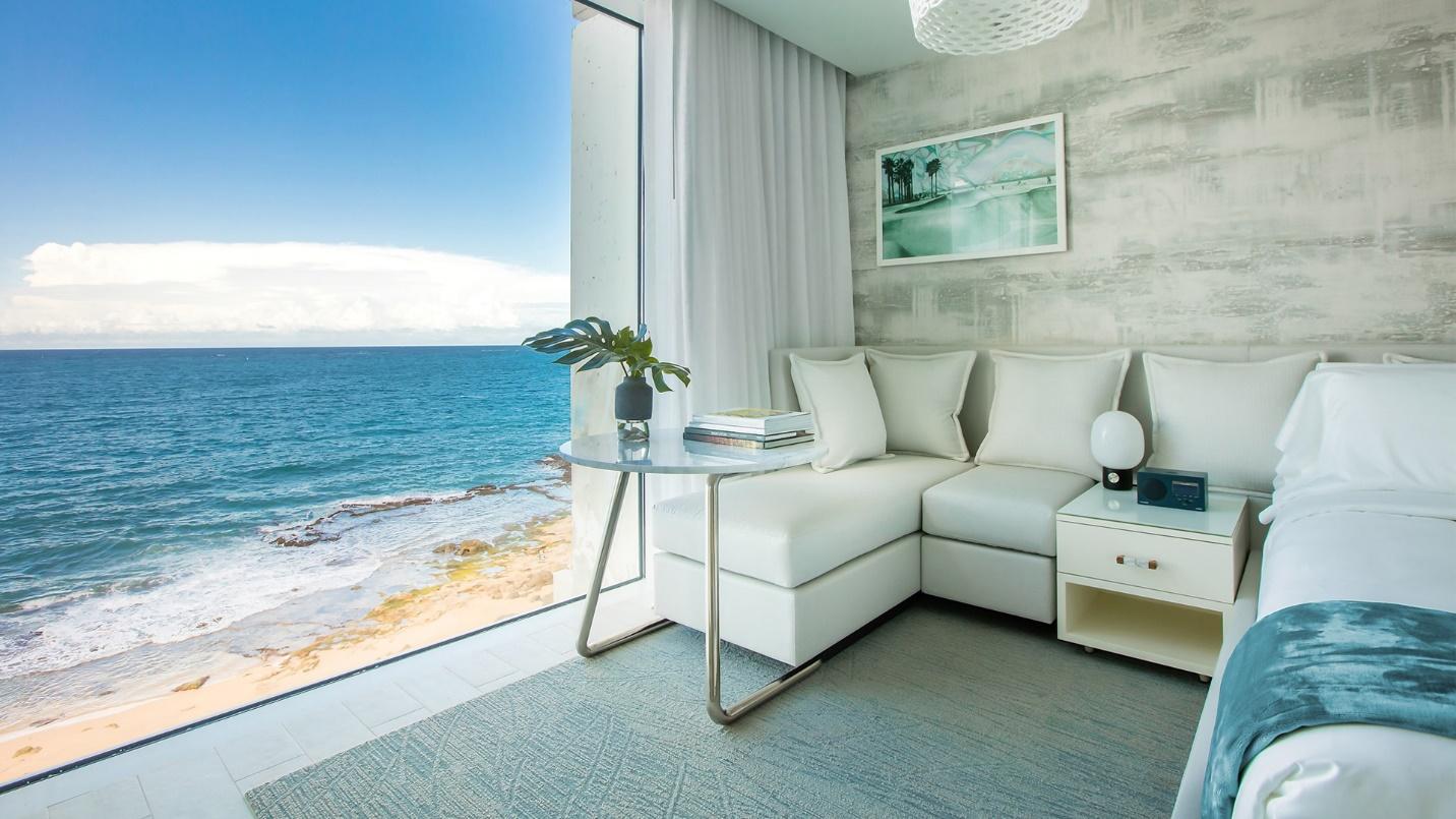 An oceanside room with floor-to-ceiling windows at Condado Ocean Club in a section describing selected hotels in the neighborhood.
