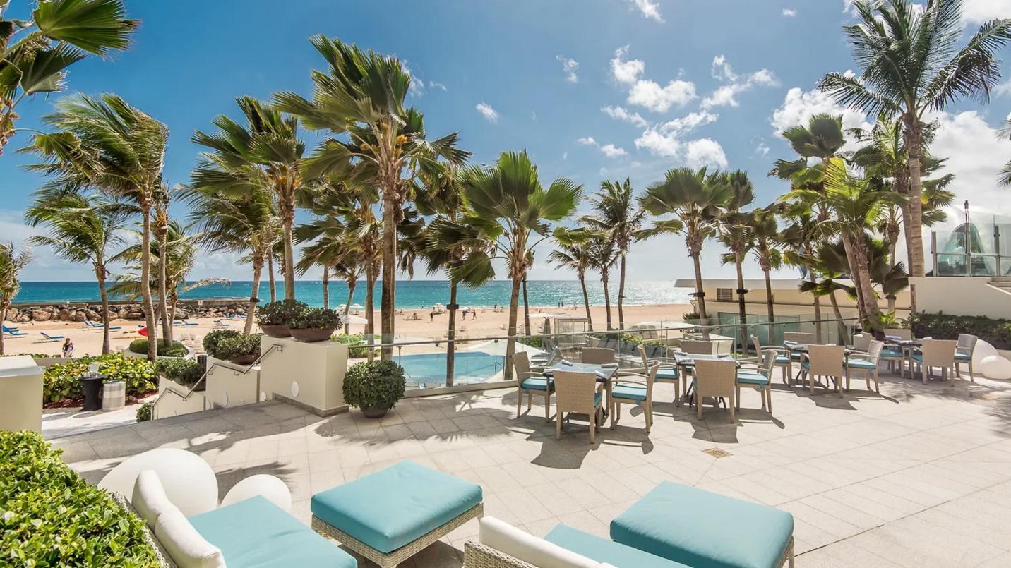 An elevated beachside sitting area and palm trees in a section about hotels in Condado.