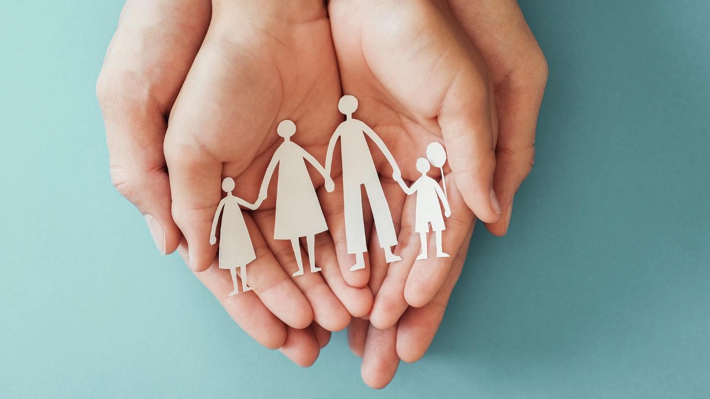 Two pairs of hands hold white paper cutouts of a family of four in a section about health care in Puerto Rico. 
