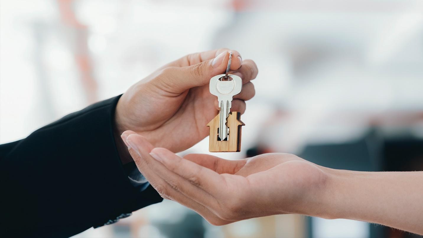 One person hands a key to another in a section about PRelocate’s real estate brokerage services and what makes Condado a desirable neighborhood. 