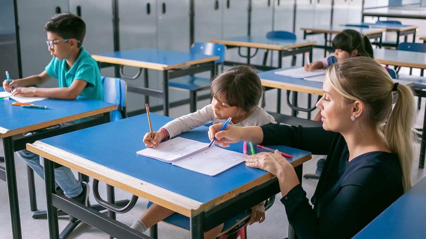 A blonde woman instructs three young students at their desks in a section about private schools in the San Juan area.