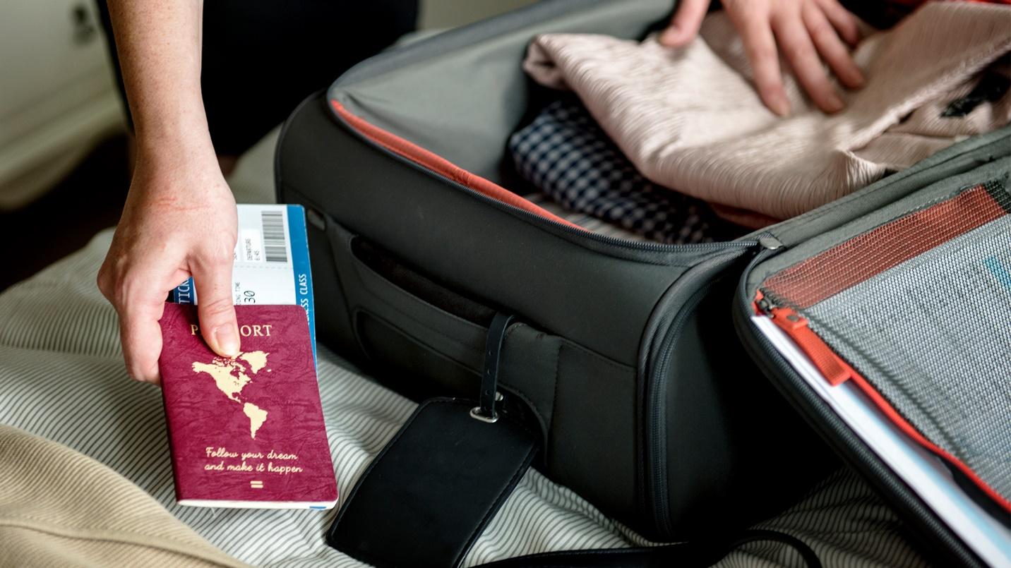 A traveler with a passport and boarding pass packs clothes into a suitcase in a section about traveling in and from Miramar.